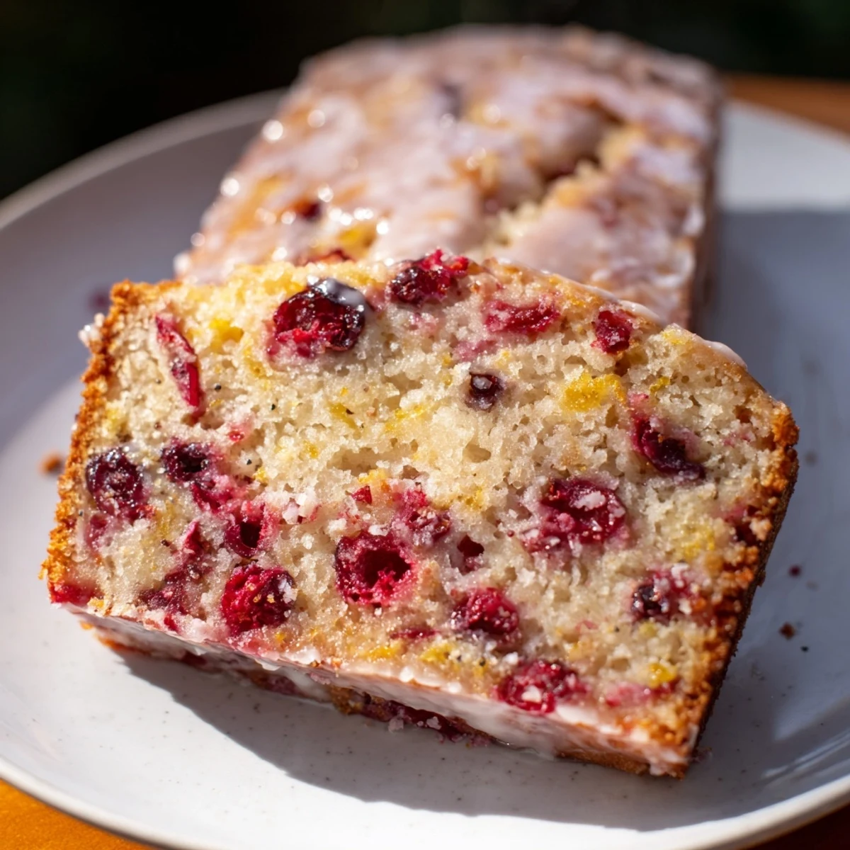 A warm slice of seasonal cranberry and orange bread, showcasing tart cranberries and orange zest.