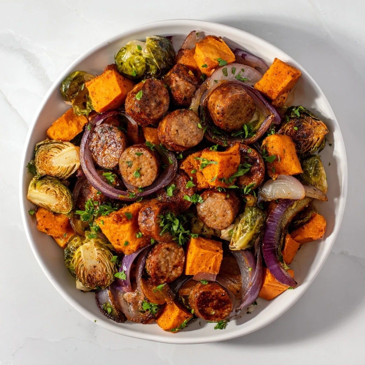Sheet pan sausage, sweet potato, and Brussels sprouts, a colorful, roasted dinner with crispy edges.