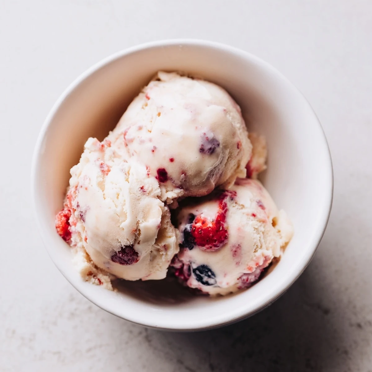 Creamy cottage cheese ice cream swirled with colorful berries, perfect for a summertime dessert.