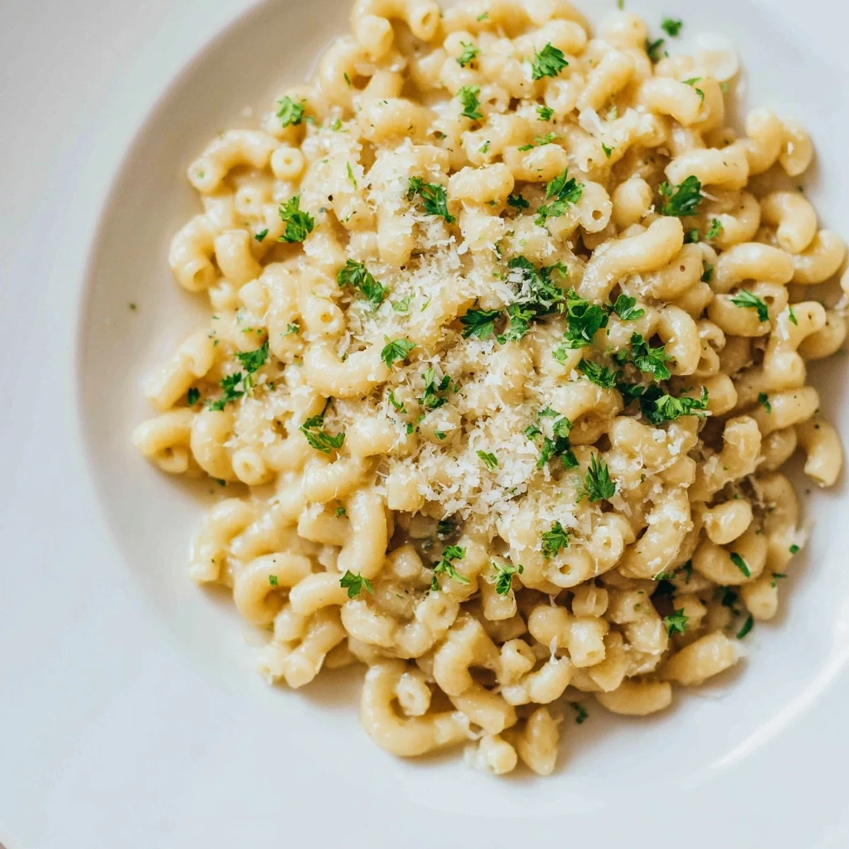 Steaming bowl of creamy garlic ditalini pasta, garnished with fresh parsley and Parmesan cheese.