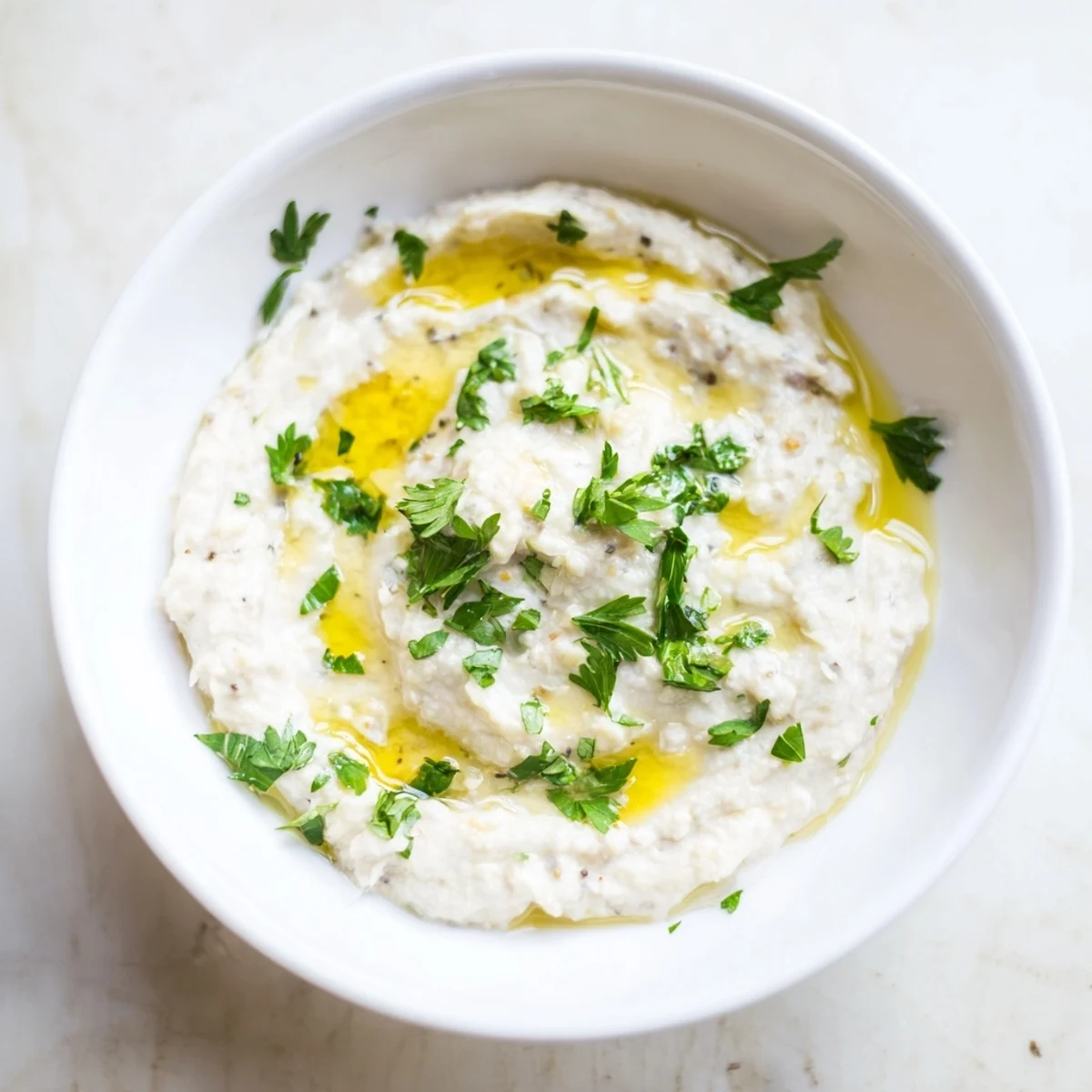 Smooth and velvety White Bean Dip in a rustic bowl, surrounded by colorful fresh veggies and warm pita bread.