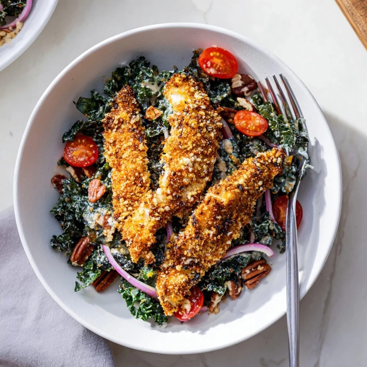 For a hearty weeknight dinner, this Crispy Chicken Kale Salad combines crispy breaded chicken, kale, and sweet-tart dressing for a satisfying, American-style meal.