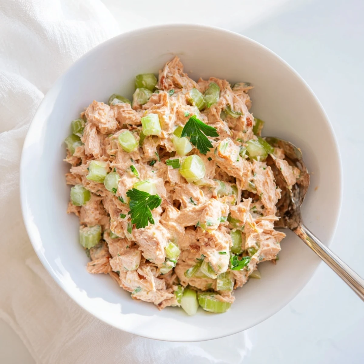 A close-up of Spicy Zesty Tuna Salad in a white bowl, featuring flaky tuna and vibrant green scallions, ready for a sandwich or wrap.