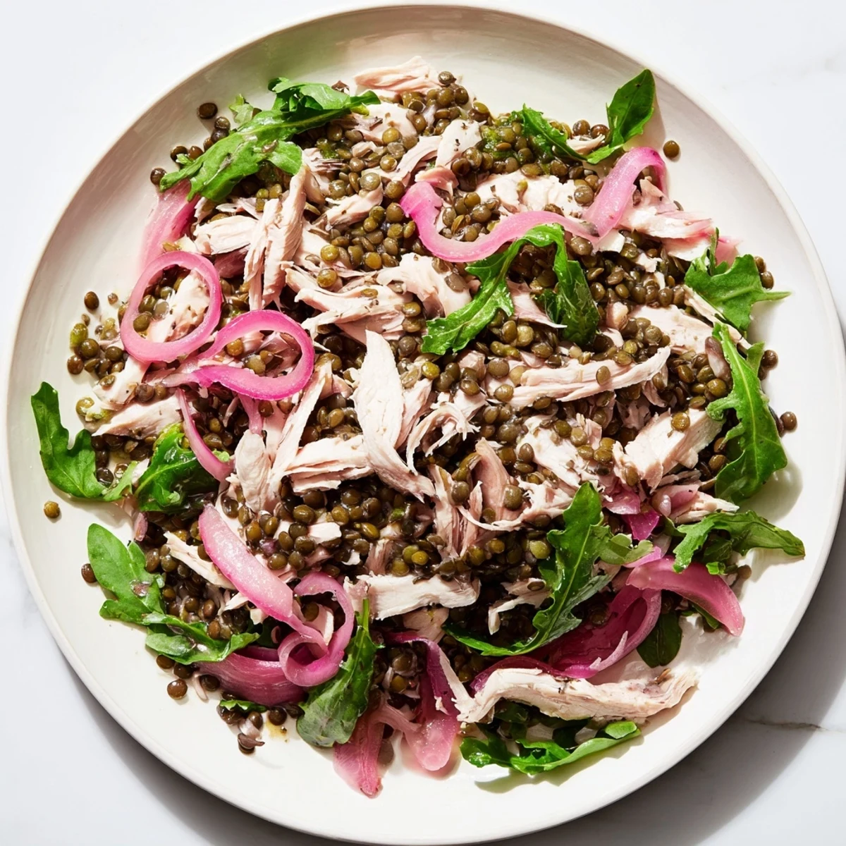 Vibrant bowl of Lentil & Chicken Spring Salad with peppery greens, golden lentils, and shredded roasted chicken tossed in tangy dressing.