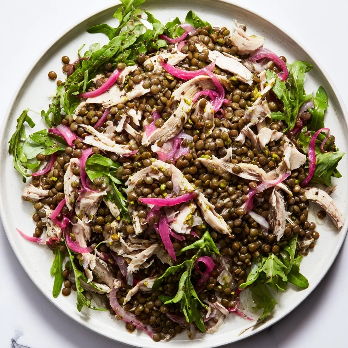 Lentil & Chicken Spring Salad plated beside a linen napkin, showcasing fresh cherry tomatoes, cucumber slices, and a drizzle of mustard dressing.