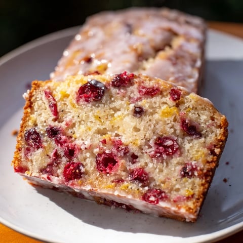 A warm slice of seasonal cranberry and orange bread, showcasing tart cranberries and orange zest.