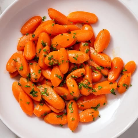 Golden honey-glazed carrots, glistening and tender, ready for serving with a sprinkle of fresh parsley.