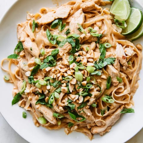 Creamy, flavorful Thai Peanut Chicken Pasta ready to be enjoyed, with a side of fresh lime wedges.