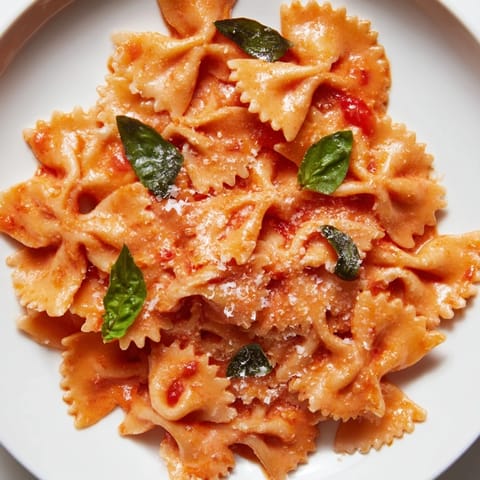 Close-up of steaming Tomato Basil Bowtie Pasta, with melted Parmesan and silky red sauce clinging to each al dente farfalle.