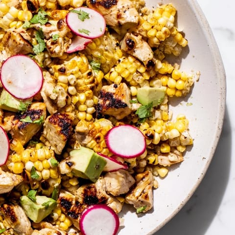 Close-up view of Roasted Corn & Chicken Chopped Salad featuring juicy diced chicken, sliced radishes, cherry tomatoes, and a zesty lime dressing.