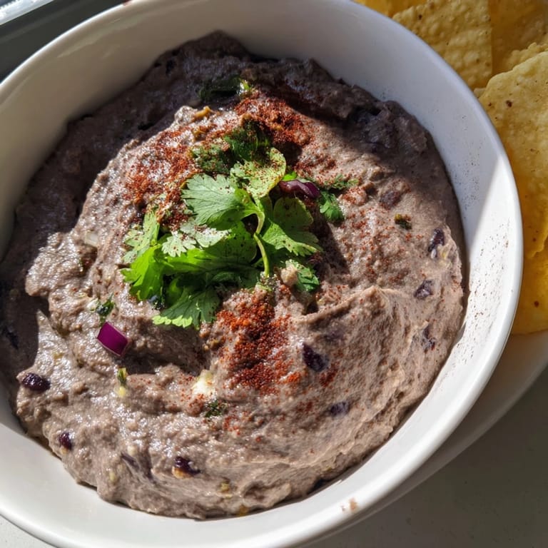 Smooth and chunky spicy black bean dip topped with sliced jalapeños and crumbled cotija cheese, ideal for taco night or family gatherings.