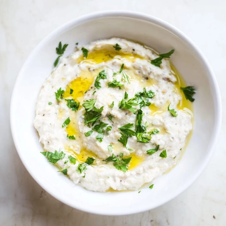 Smooth and velvety White Bean Dip in a rustic bowl, surrounded by colorful fresh veggies and warm pita bread.