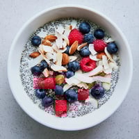 Creamy Poppy Seed Chia Pudding in a glass jar, topped with fresh blueberries, raspberries, and toasted almonds.